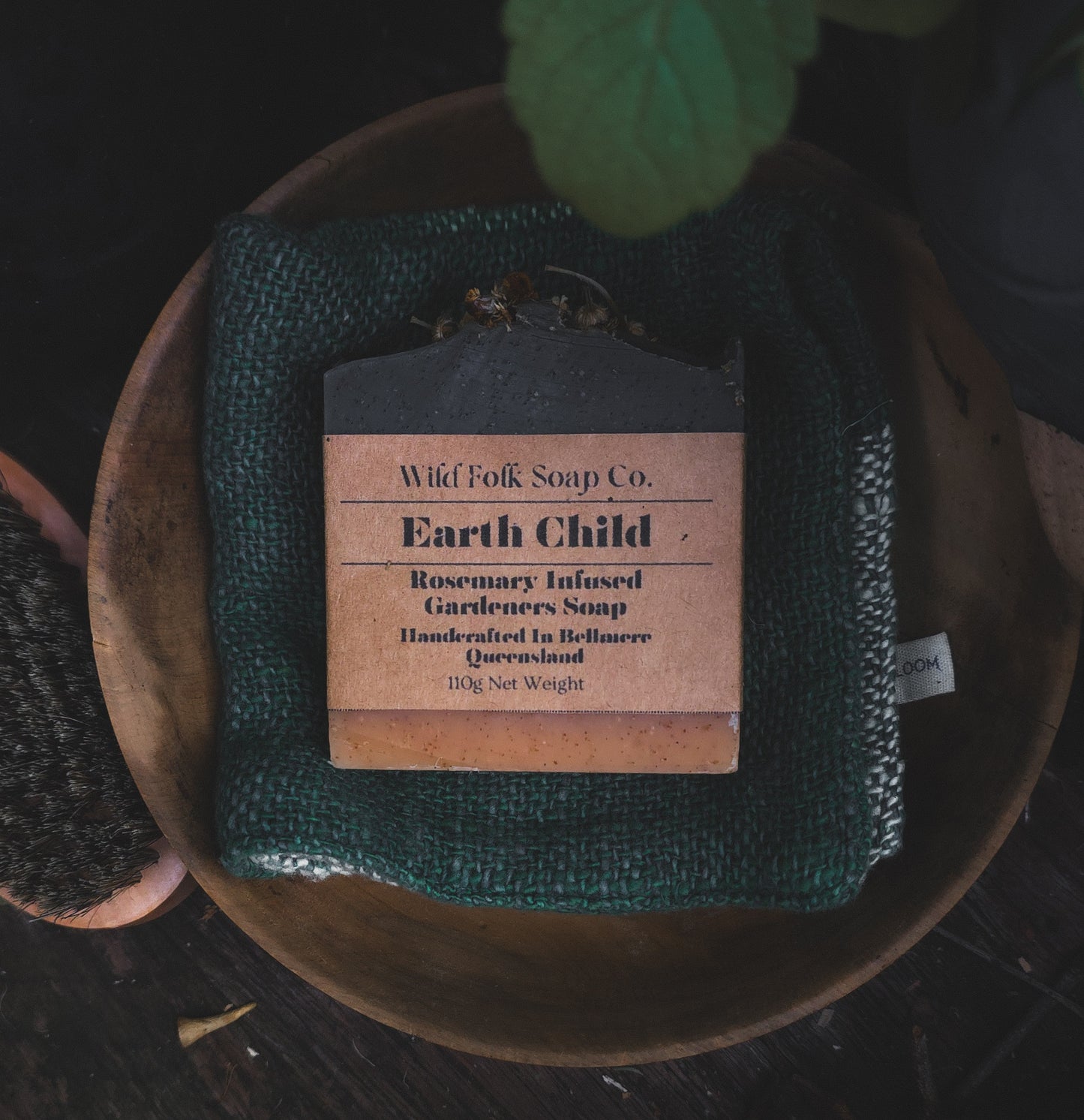 Wild Folk Soap Co. Earth Child soap bar on a wooden plate with a dark background