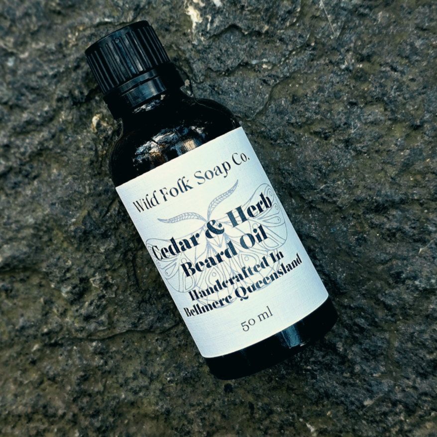 Bottle of Cedar & Herb Beard Oil from Wild Folk Soap Co. on a textured stone surface
