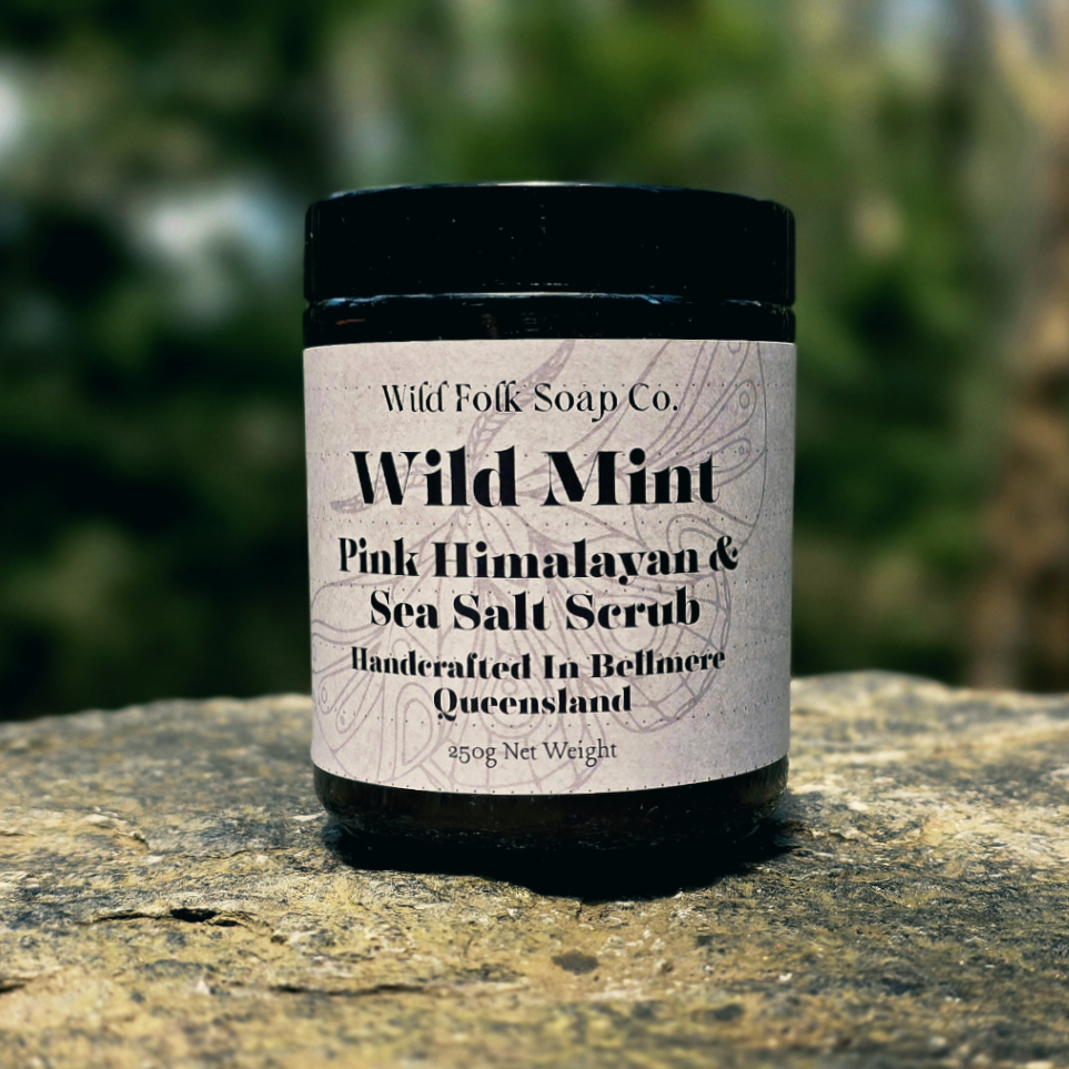 Jar of Wild Mint Pink Himalayan & Sea Salt Scrub from Wild Folk Soap Co. on a rock with a blurred natural background.