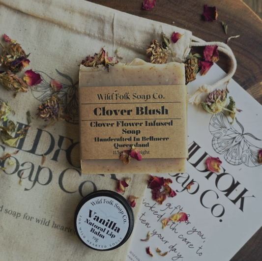 Bar of soap with packaging and a lip balm on a surface with 'Wild Folk Soap Co.' branding.