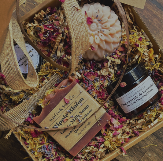 Gift set with soap, candle, and essential oil bottle on a wooden surface