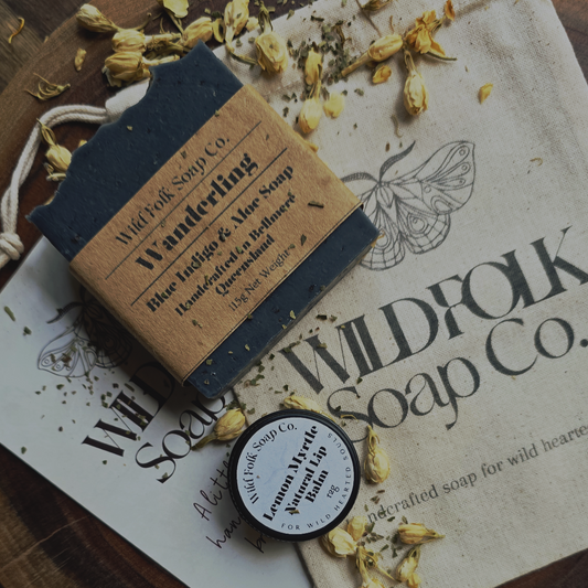 Bar of soap with a label on a Wildfolk Soap Co. branded surface with dried flowers.