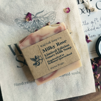 Bar of soap with a wooden box labeled 'Wild Folk Soap Co. Milky Rose' on a textured surface.